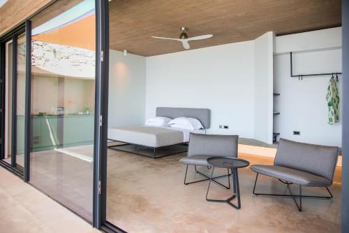 a bedroom with a bed and two chairs and a table at Echoes Milos in Kástron