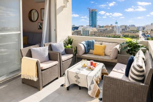 a balcony with wicker chairs and a table at Bright spacious getaway close to the Sea in Il-Gżira