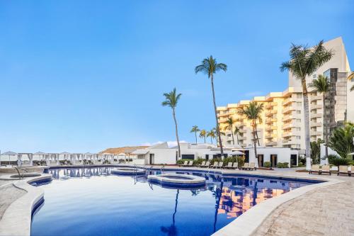 a large swimming pool with palm trees and buildings at Sunvivia by Fiesta Americana Mazatlán in Mazatlán