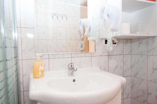 a white bathroom with a sink and a mirror at Rooms Garden Zagreb Airport in Velika Gorica