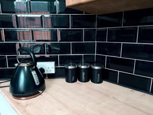 a tea kettle and three cups on a counter at Cozy corner - 3 Bedroom Full House - Perfect for Families, Couples And Company Contractors in Wakefield