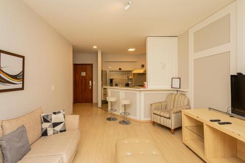 a living room with a couch and a kitchen at SEQ - Sequoia Alphaville By Anora Spaces in Barueri
