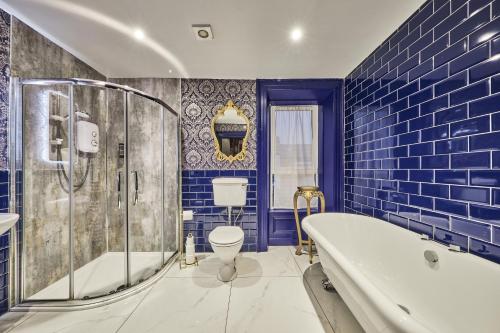 a blue bathroom with a tub and a toilet at Jazz House in Derry Londonderry