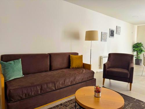 a living room with a brown couch and a chair at Apartamentos Fonte Velha in Ponte da Barca