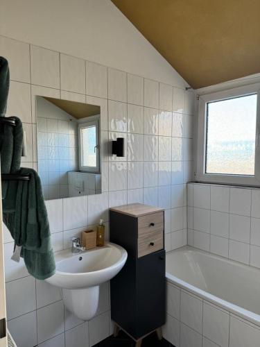a white bathroom with a sink and a bath tub at Helle Dachgeschoßwohnung am Laurentiusplatz in Wuppertal