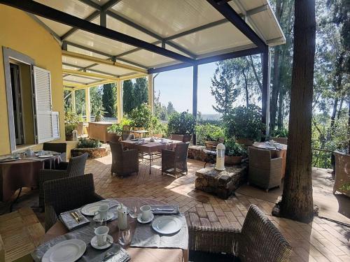 a patio with tables and chairs and a large window at Quinta das Eirinhas-Jardim de Bonsai in Tavira
