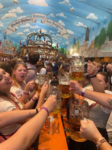 a group of people holding up glasses of beer at Beer Base-Camp 'BASIC PACKAGE' Oktoberfest Camping, with free welcome beer and traditional lederhosen-dirndl shop in Munich