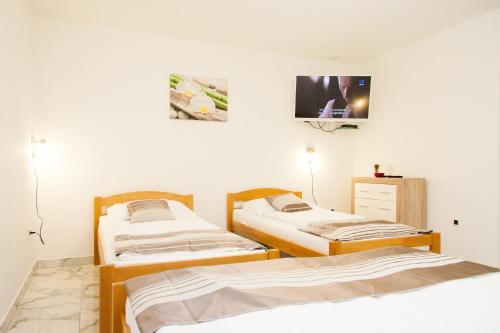 three beds in a room with a tv on the wall at Rooms Garden Zagreb Airport in Velika Gorica