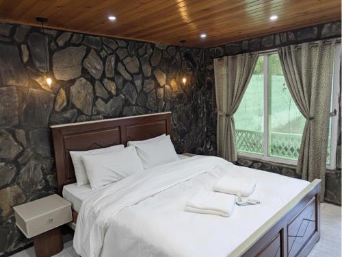 a large bed in a room with a stone wall at Comfort Hotel & Huts in Skardu