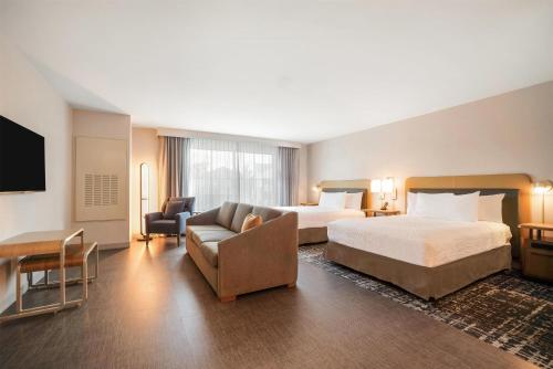 a hotel room with two beds and a couch at Homewood Suites By Hilton Madison Huntsville in Madison