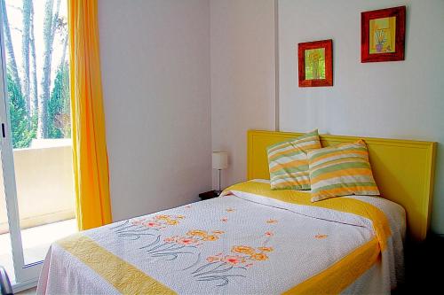 a bedroom with a bed with a yellow headboard and a window at Dunas I, 3 in Pinamar