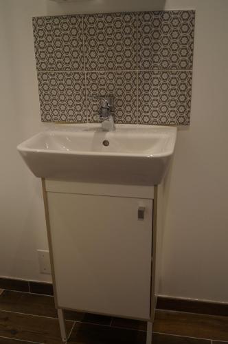 La salle de bains est pourvue d'un lavabo blanc et d'un mur. dans l'établissement L'atelier, à Cancale