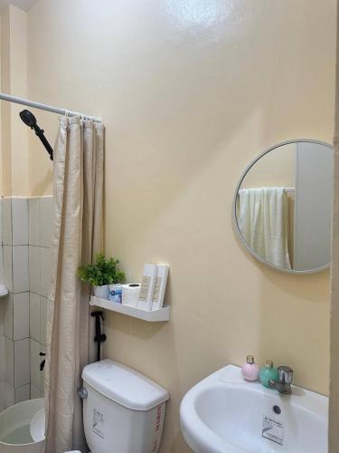 a bathroom with a toilet and a sink and a mirror at Luxy Stay Gensan in Lagao II