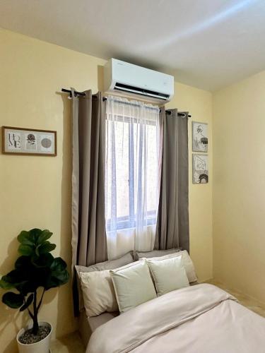 a bedroom with a window and a bed with pillows at Luxy Stay Gensan in Lagao II