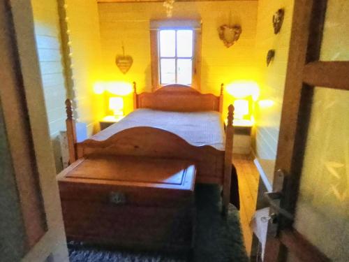 a bedroom with a bed and two lamps and a window at Trevenna Cabin in St Austell