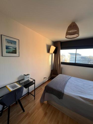 a bedroom with a bed and a table and a window at Chambre vue parc chez l'habitant in Annecy