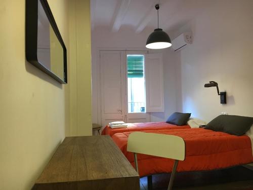 a bedroom with a bed with a red blanket and a window at Hostal Portugal in Barcelona