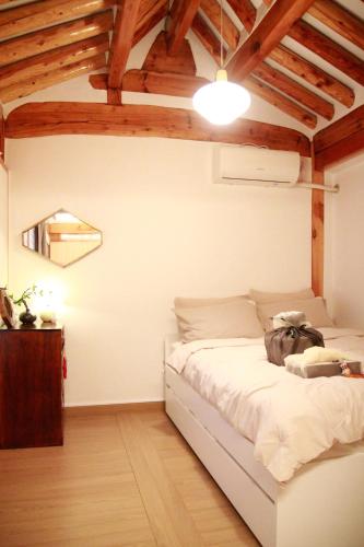 a bedroom with a white bed in a room with wooden ceilings at Moonjarak Dalbit Hanok in Seoul