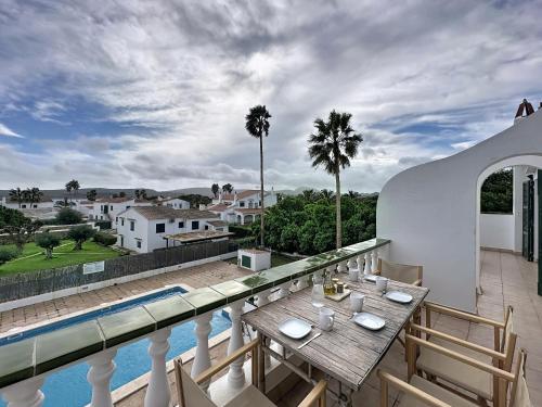 a balcony with a table and a swimming pool at Apartamento con piscina SS20 in Fornells