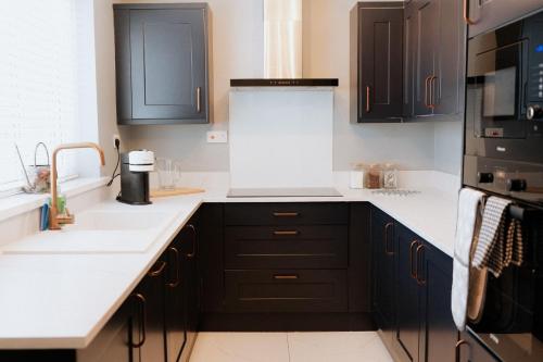 a kitchen with black cabinets and white counter tops at Meldon Cottage with Private Hot Tub in Newbiggin-by-the-Sea