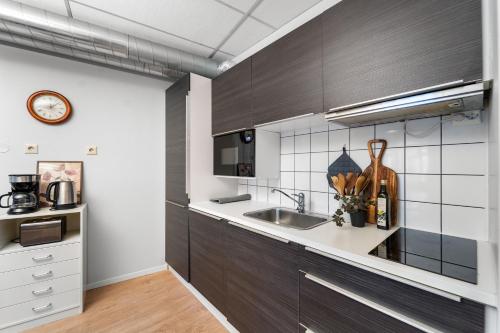 a kitchen with dark wood cabinets and a sink at Tromso Downtown Apartments - Main Street in Tromsø