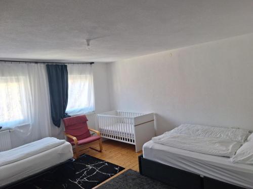 a bedroom with two beds and a chair and a crib at Delblaiso Suite in Memmingen