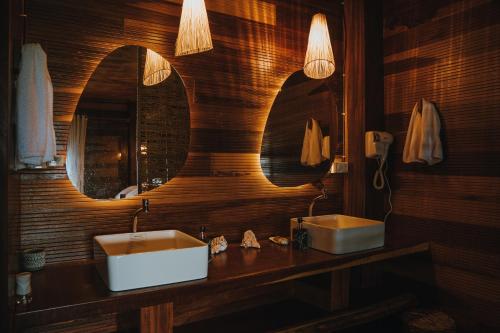 a bathroom with two sinks and two mirrors at Áurea chalés in Tutóia