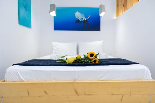 a bed with a blue blanket and flowers on it at MNS Accommodations in Salamina