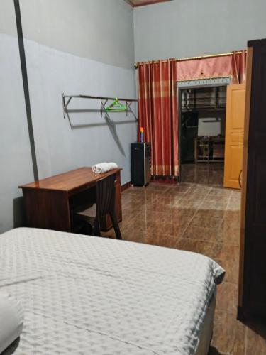 a bedroom with a bed and a desk and a table at Keluncing Field Homestay in Kotaraja