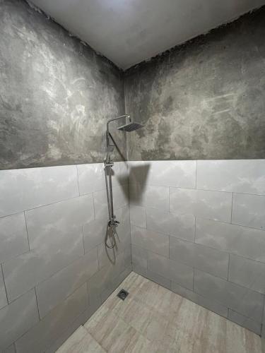 a bathroom with a shower with white tiles at Keluncing Field Homestay in Kotaraja