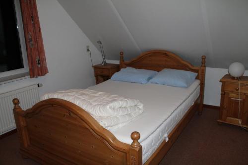 um quarto com uma cama de madeira com lençóis brancos e almofadas azuis em duin/vuurtorenzicht em De Cocksdorp