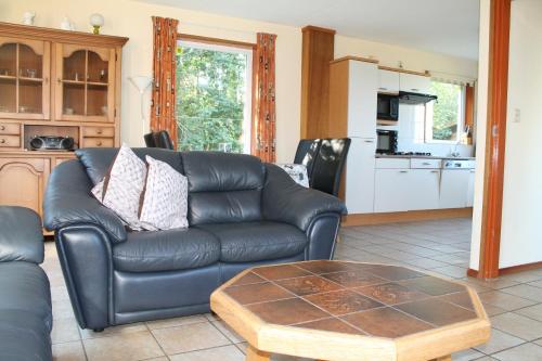 uma sala de estar com um sofá de couro e uma mesa de centro em duin/vuurtorenzicht em De Cocksdorp