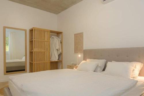a bedroom with a large white bed and a mirror at Villa Sunrise Labin Istria - a smile every day in Nedeščina