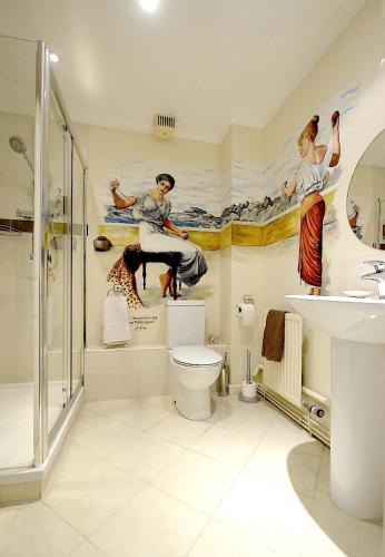a bathroom with a shower toilet and paintings on the wall at Meryan House Hotel in Taunton