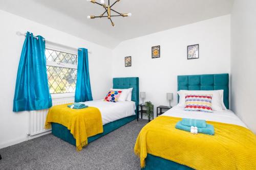 two beds in a bedroom with blue curtains and yellow blankets at Temple by Alt-Stay Contractor Accommodation - 4 Bed Contractor Home With Parking, Wi-Fi & Full Kitchen - Ideal For Long stays in Leeds