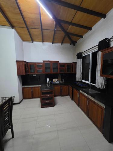 a large kitchen with wooden cabinets and black counter tops at X38 Venture in Kitulgala