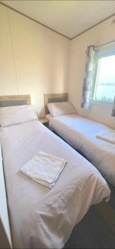 two beds in a room with a towel on them at Shellie's Summer Breeze Retreat in Heysham