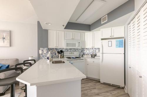 a kitchen with white cabinets and a white refrigerator at Oceanview Modern 1BR, king bed at Carolinian Resort" in Myrtle Beach