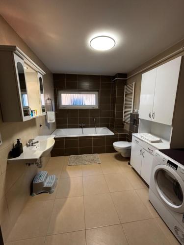 a bathroom with a tub and a sink and a washing machine at Maxi Apartman in Budaörs