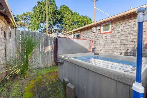 a hot tub in a backyard next to a fence at The Lily Pad in Rockaway Beach