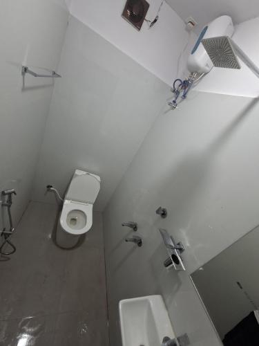 a white bathroom with a toilet and a sink at Dolphin beach resort in Varkala