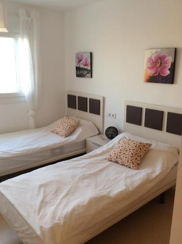 two beds in a room with white walls at Condado de Alhama N478 in Alhama de Murcia