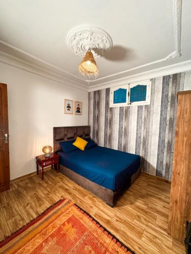 a bedroom with a blue bed and a chandelier at Quiet Private Room in Tiznit in Tiznit