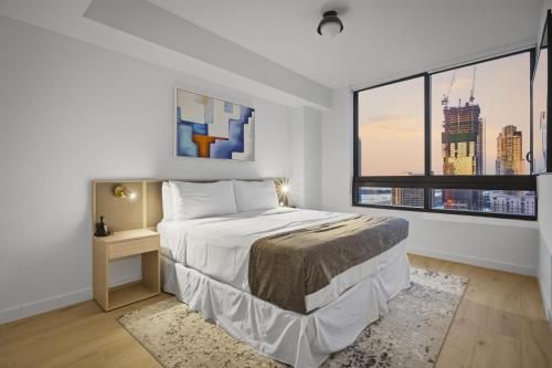 a white bedroom with a bed and a large window at Upscale Downtown Condo Pool Gym & Skyline Views in Miami