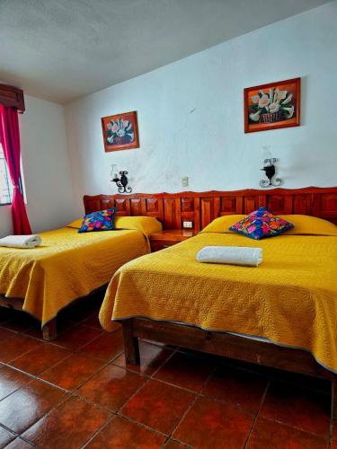 deux lits dans une chambre avec des draps jaunes dans l'établissement Hotel San Luis, à San Cristóbal de Las Casas