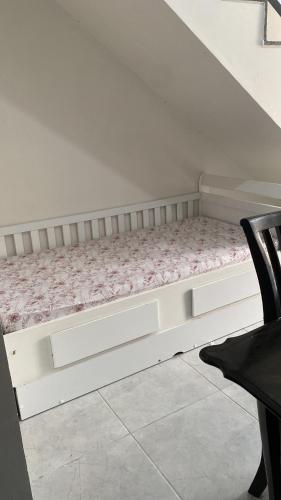 a white bed in a room next to a chair at Lar Aconchego climatizado e compartilhado in Aracaju