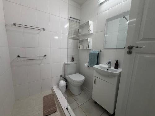 a white bathroom with a toilet and a sink at Withuis Hartenbos - No Load Shedding in Hartenbos