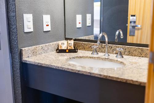 a bathroom counter with a sink and a mirror at Hotel 10 Curitiba in Curitiba