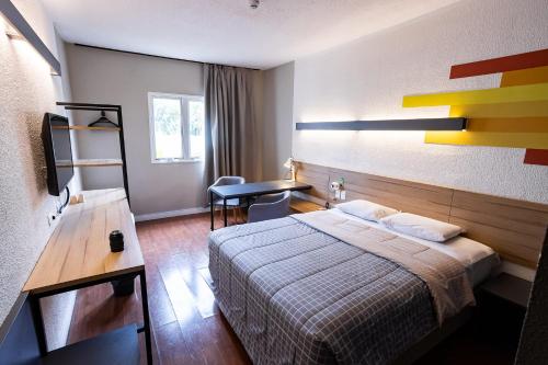 a hotel room with a bed and a desk at Hotel 10 Curitiba in Curitiba