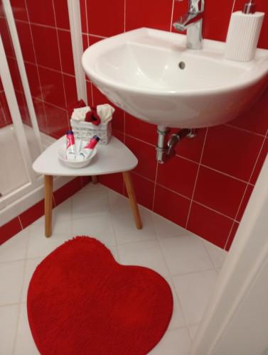 a red bathroom with a sink and a red heart rug at Appartamento rosso blu in Vernazza